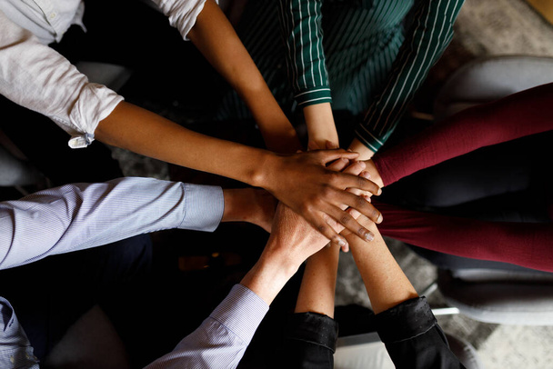 Позитивна різноманітна бізнес команда кладе руки один на одного, демонструючи єдність і командну роботу
 - Фото, зображення