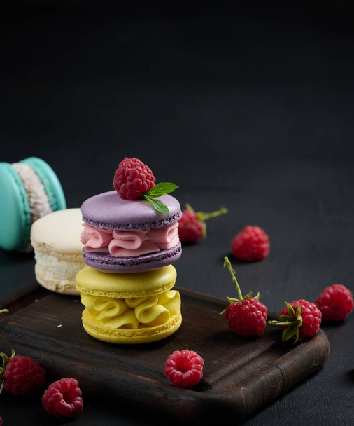 A stack of multi-colored macaroons on a wooden board. Delicious dessert - Zdjęcie, obraz