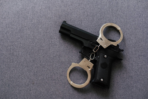 Black gun and metal handcuffs lie on the black background. Private detective work. Searching information. Crime and robbery, prison concept - Foto, Imagem