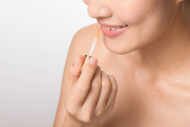 Mooi portret jonge aziatische vrouw op zoek spiegel aanbrengen make-up lippenstift op kamer. - Foto, afbeelding
