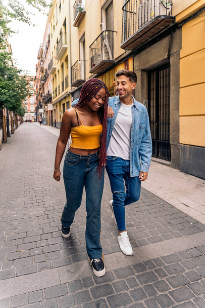 Cheerful multi-ethnic young couple walking in the streets of Madrid and having fun. - Fotoğraf, Görsel