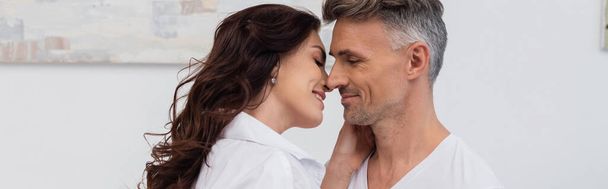 Smiling brunette woman in shirt kissing husband at home, banner  - Foto, imagen