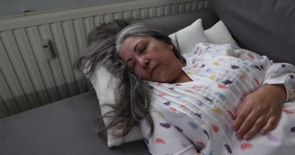 ired donna adulta che dorme rilassata su cuscini sul divano dopo una lunga giornata di lavoro, riposino rilassante, girando la testa, vestiti casual, lunghi capelli neri grigi. Concetto di vita quotidiana - Filmati, video