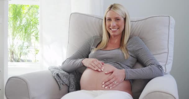 Uśmiechający się kobieta w ciąży brzuch tarcie w przedszkolu - Materiał filmowy, wideo