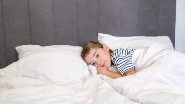 Küçük bir kız yatakta yan yatmış uyuyor. 8-9 yaşındaki bir kız beşiğinde uyuyakalıyor. 4k video - Video, Çekim
