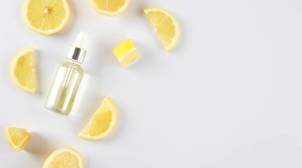 Бутылка с лимонным эфирным маслом с ломтиками лимона на столе. Косметическое цитрусовое масло или сыворотка. Естественная медицина. Ароматерапия - Фото, изображение