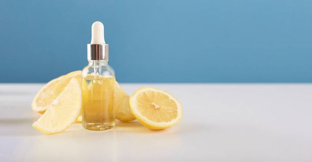 Bottle with lemon essential oil with lemon slices on table. Cosmetic citrus oil or serum. Natural medicine concept. Aromatherapy - Valokuva, kuva