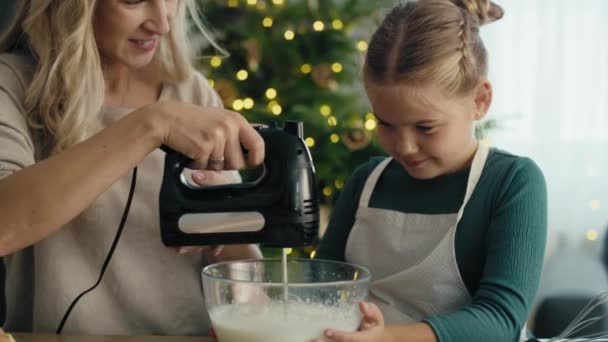 Kaukázusi anya és lánya sütésre készül elektromos mixerrel a konyhában karácsony előtt. Lövés RED hélium kamerával 8K-ban.    - Felvétel, videó
