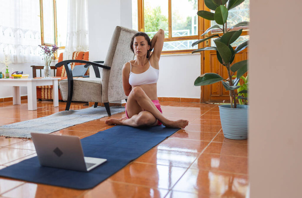 the girl is engaged in breathing practices at home online. yoga classes at home. young woman starts doing yoga. - Fotó, kép