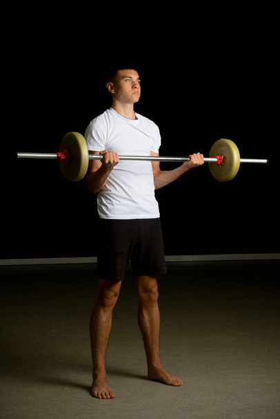19 year old teenage boy excercising his biceps with a barbell - Фото, зображення