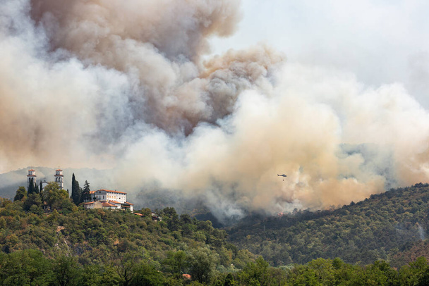 Helicóptero contra incendios forestales durante fuerte viento y sequía cerca del Castillo Miren en Eslovenia - Foto, Imagen