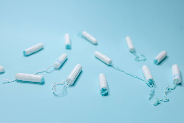 Various sanitary tampons lie on a light blue background. Menstrual cycle and pregnancy. - 写真・画像