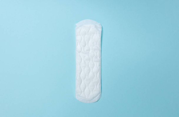 Sanitairpads liggen op een lichtblauwe achtergrond. Menstruatiecyclus en zwangerschap. Negatieve zwangerschapstest en anticonceptiva - Foto, afbeelding