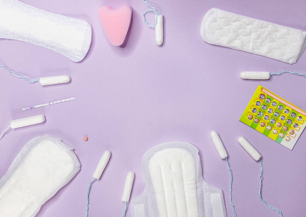 Fioletowo-biały test ciążowy z jednym paskiem, podpaską higieniczną i pigułkami antykoncepcyjnymi leży na fioletowym tle. Cykl menstruacyjny i ciąża. Negatywny test ciążowy i środki antykoncepcyjne - Zdjęcie, obraz