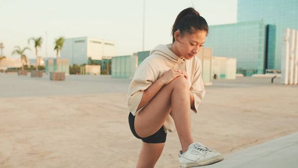 Asian girl in sportswear does workout, stretching and gymnastics on modern buildings background - Foto, immagini