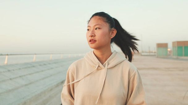 Close up, asian girl in sportswear stands at morning time on modern buildings background - Fotografie, Obrázek