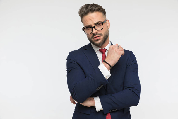 koele elegante man met bril houden armen in de mode pose en poseren voor witte achtergrond in de studio - Foto, afbeelding