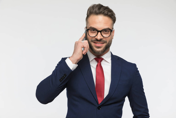 retrato de empresário feliz com óculos falando no telefone e sorrindo na frente de fundo branco em estúdio - Foto, Imagem