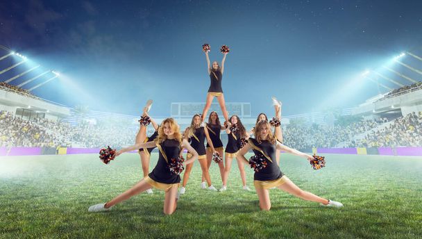 Ryhmä cheerleadereita toiminnassa stadionilla yöllä - Valokuva, kuva