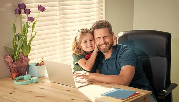 ευτυχισμένος πατέρας βοηθώντας το σχολείο γιος του μελέτη με φορητό υπολογιστή στο σπίτι, παιδική ηλικία. - Φωτογραφία, εικόνα