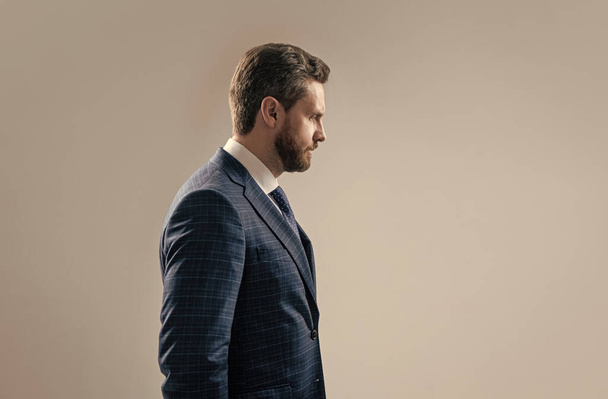 Serious business professional man stand sideway in formal suit grey background copy space, businessman. - Fotó, kép