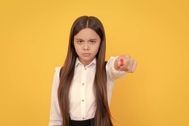 Serious frown school girl point pen putting out hand yellow background, back to school. - Foto, Imagen