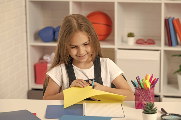Lächelndes Kind schneidet Papier im Klassenzimmer. - Foto, Bild