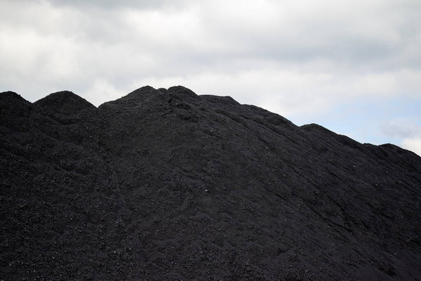 Une énorme montagne de charbon noir dans un concept de crise énergétique et de pénurie d'énergie avec un ciel gris en arrière-plan - Photo, image