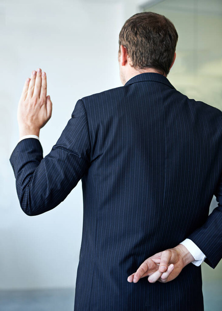Prácticas empresariales poco éticas. un hombre de negocios cruzando los dedos a sus espaldas - Foto, imagen