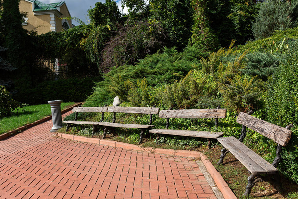 公園内の広場のベンチの風景、道はタイルで舗装されています。 - 写真・画像