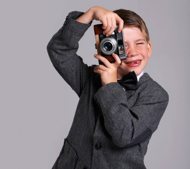 Nuori Weegee. Studio-kuva nuoresta pojasta vanhassa puvussa, jolla on vintage-kamera - Valokuva, kuva