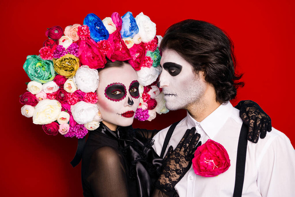 Love melt dead hearts. Photo of creepy frightening couple man lady cuddle dark monster creatures wear black dress death costume roses headband suspenders isolated red color background. - Foto, immagini
