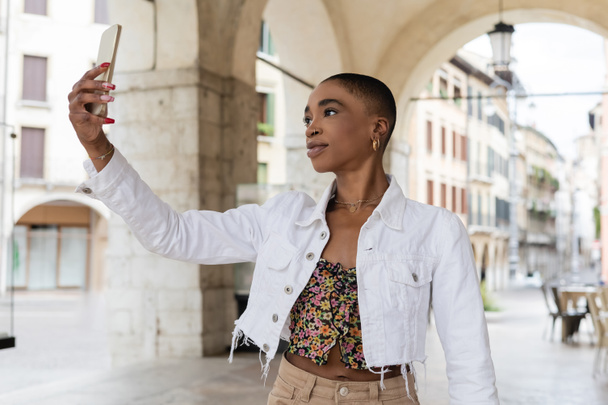 Krótkowłosy Afroamerykanka robi selfie na smartfonie na ulicy miejskiej w Treviso - Zdjęcie, obraz