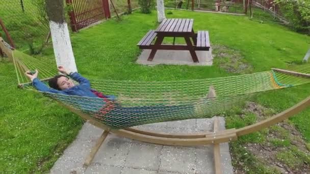 Peaceful attractive young woman relaxing in a hammock on vacation. Healthy calm girl relaxing on a comfortable outdoor swinging hammock, dream, stress-free, relaxing on vacation, dreaming of good - Záběry, video