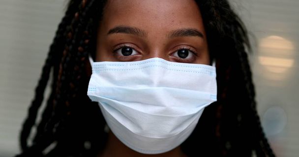 Black preteen girl putting covid-19 face mask prevention - Фото, изображение