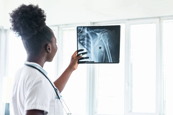 Closeup portrait of intellectual healthcare professional with white labcoat, looking at full body x-ray radiographic image, ct scan, mri, isolated hospital clinic background. Radiology department - Foto, afbeelding