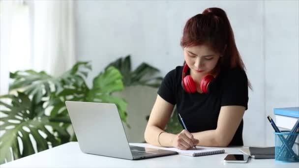 Esta hermosa mujer asiática es una estudiante universitaria, está haciendo videollamadas con sus compañeros de clase a través de una computadora portátil para discutir el trabajo en grupo en un curso conjunto. Concepto de uso de la tecnología para comunicarse. - Metraje, vídeo