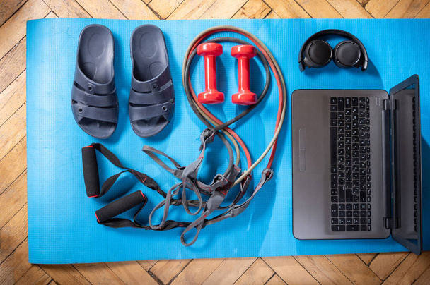Medence papucs és laptop. Fitness tárgyak és laptop. Gumibővítők és piros súlyzók. Dumbbellek és laptop. Kilátás felülről. - Fotó, kép