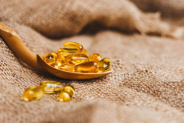 Vitamínový komplex omega 3,6,9. Tobolky s rybím olejem na dřevěné lžičce. Prášky na rybí tuk, tablety na nohavici. Kopírovat prostor - Fotografie, Obrázek