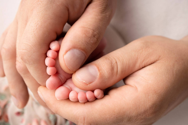 Mother and father are doing massage on her baby foot. Closeup baby feet in mother hands. Prevention of flat feet, development, muscle tone, dysplasia. Family, love, care, and health concepts.  - Fotó, kép
