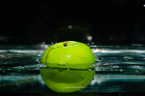 green apple thrown into water with splashes and bubbles. green apple in water - Foto, Imagem