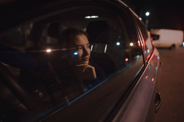 Woman portrait in a car at the night relaxing looking through window - Foto, Bild