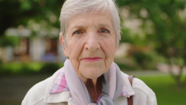 Senior woman portrait in a park for retirement or wellness, healthy and green lifestyle with trees and bokeh. Elderly lady face, enjoying outdoor nursing home or nature fresh air for mental health. - Video, Çekim