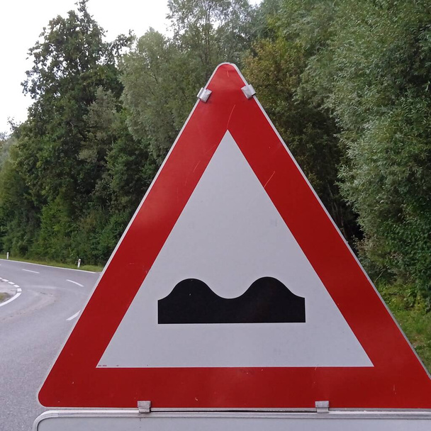wyboje i fale naziemne przed znakiem drogowym, ostrzeżenie z czerwonym trójkątem - Zdjęcie, obraz