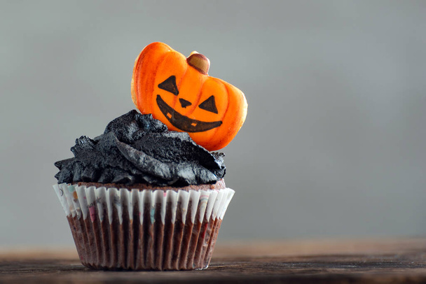 Halloween cupcake with decorations gingerbread pumpkins on grey background. Homemade muffins - Photo, Image