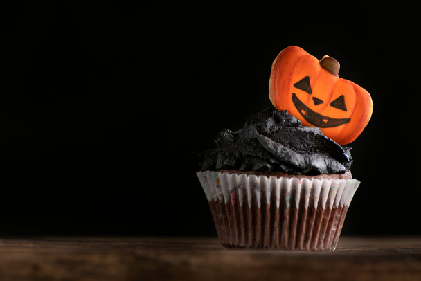 Heerlijke Halloween feest zwarte cupcake met peperkoek pompoenen op zwarte achtergrond. Kopieerruimte - Foto, afbeelding