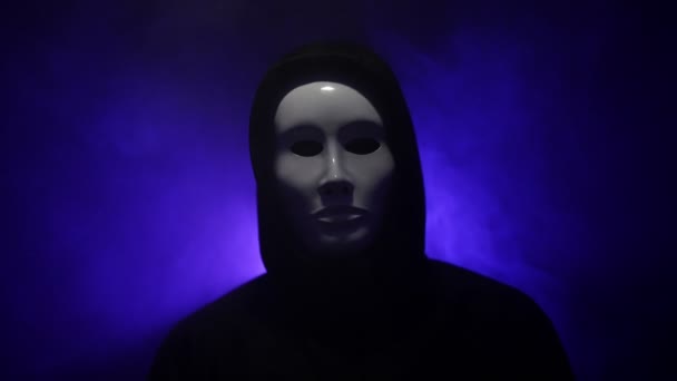 Mann trägt Maske mit Kapuzenpulli auf blauem Hintergrund. - Filmmaterial, Video