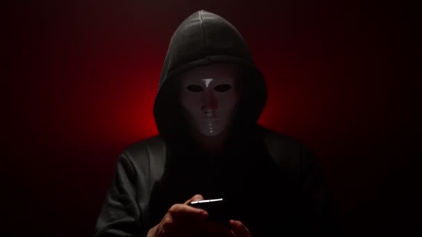 Homme portant un masque avec sweat à capuche lance le virus du smartphone. - Séquence, vidéo