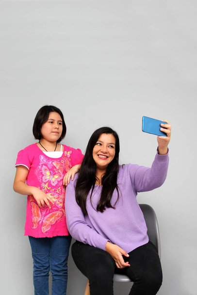 Hispanique latino maman et fille jouer, danser, surprendre, profiter, prendre des selfies en utilisant le téléphone portable passer du temps en famille de qualité - Photo, image