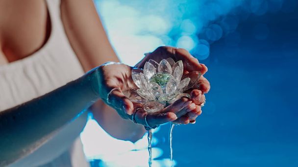 Woman holding fragile lotus flower. Clean water drops are dripping from crystal. Concept of religion, kundalini, meditation, chakras, spiritual inner world. High quality photo - Valokuva, kuva